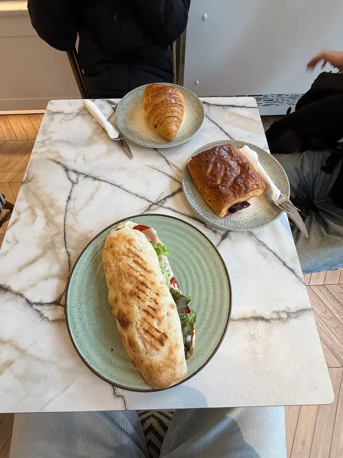 Gegrilltes Sandwich, Croissant und Schokoladengebäck auf einem Marmortisch
