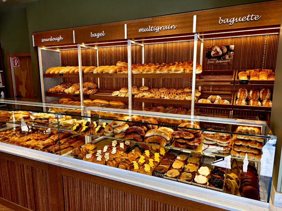 Brotregal mit Sauerteig, Bagel, Multigrain und Baguette hinter der Theke