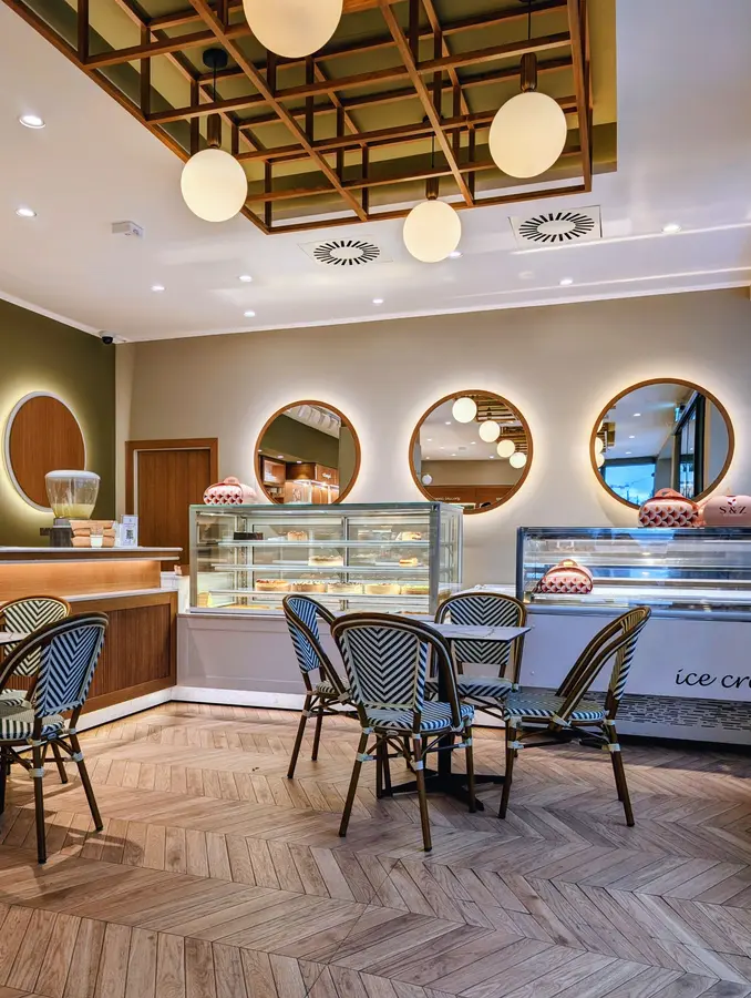Der Gastraum mit runden, beleuchteten Spiegeln, Kugellampen und gestreiften Bistrostühlen