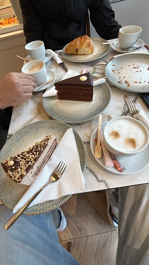 Ein Tisch mit Schokotorte, Nusstorte, Croissant und Cappuccino